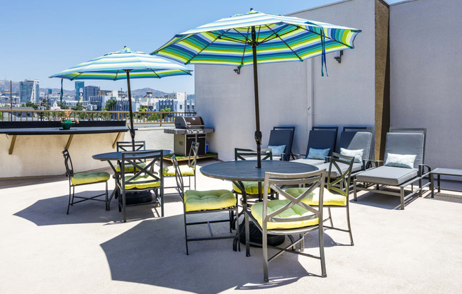 a patio with tables and chairs and umbrellas on the roof of a building