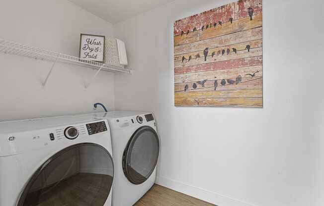 a washer and dryer in a laundry room with a painting on the wall