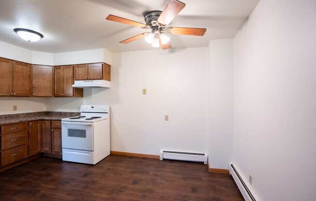 an empty kitchen with white appliances and a ceiling fan. Fargo, ND Crown Court 1 Apartments