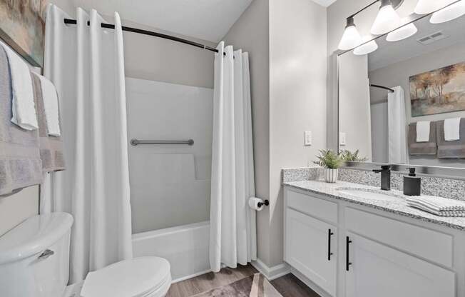 A white bathroom with a toilet, sink, and shower.