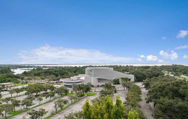 A modern building with a curved roof is surrounded by trees and open land at Hampton Apartments, Florida, 33759