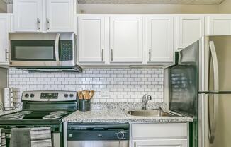 an updated kitchen with white cabinets and stainless steel appliances