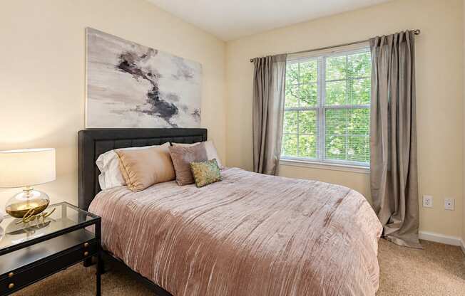 Bedroom with blush bedding, a dark upholstered headboard, and a large window at Elevation 3505 in Atlanta, GA.