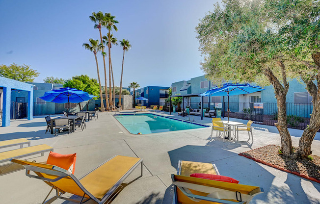 A pool area with sun loungers and a tree.