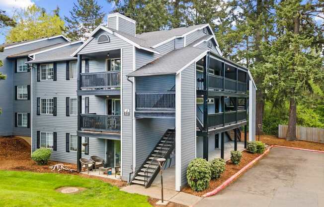 A grey two story apartment building with a balcony on the second floor.