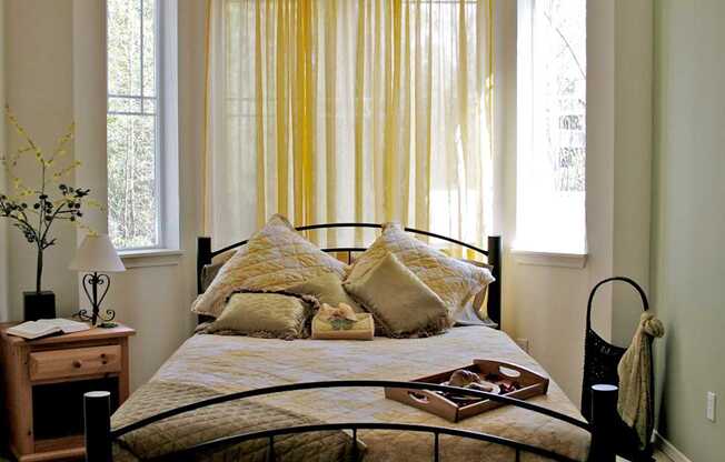 A bed with a yellow comforter and a black headboard.