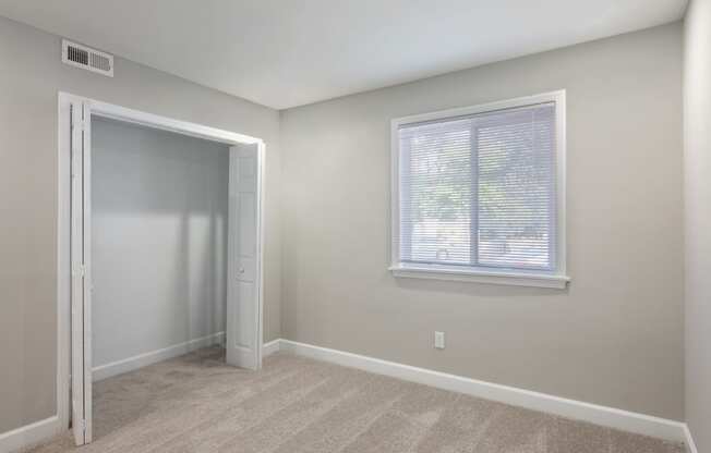 a bedroom with a large window and a closet