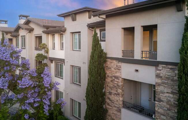 A building with a balcony and a tree in front of it.