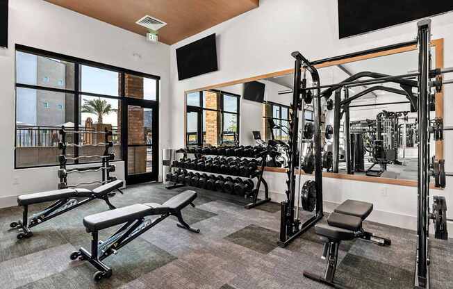 A gym with a variety of equipment including a squat rack, bench, and weights.