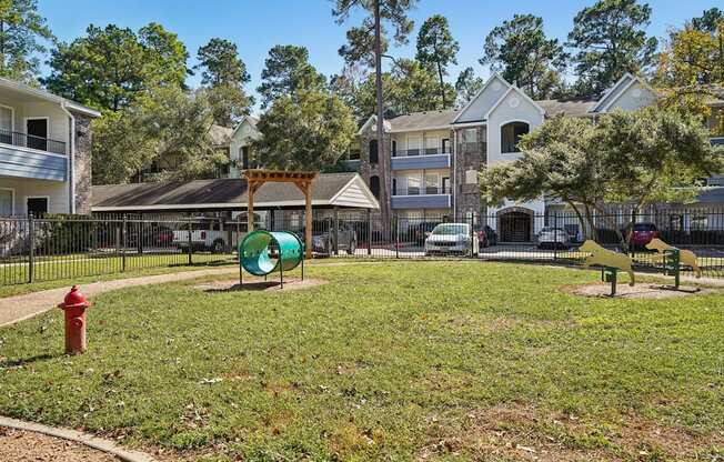 A park with a red fire hydrant and a green playground.