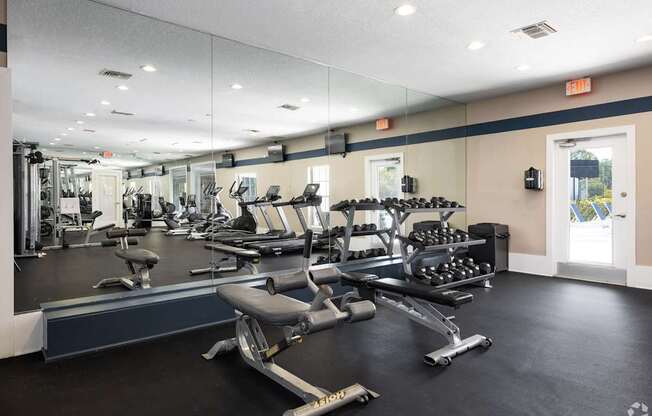A gym with a variety of equipment including treadmills, weights, and exercise machines.