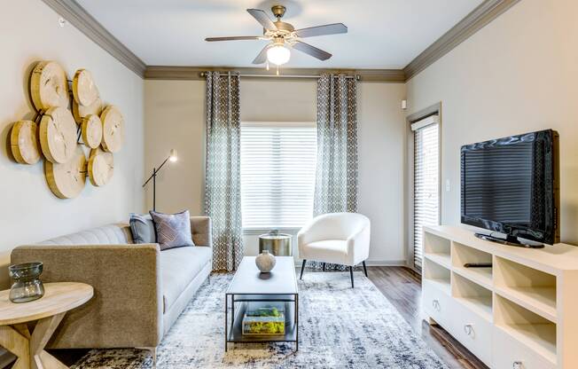 Spacious living room with ample seating, hardwood-style flooring, and ceiling fan at Avenues at Craig Ranch apartments for rent
