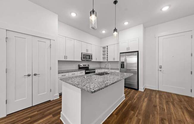 A kitchen with a granite countertop and wooden floors.