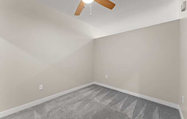 A room with a ceiling fan and a carpeted floor.