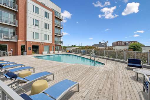 A wooden deck with a pool and sun loungers at The Waterford At Rocketts Landing Apartments, PRG Real Estate, Richmond, Virginia