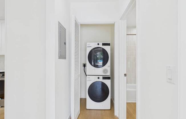 A white dryer and washer are in a narrow hallway.