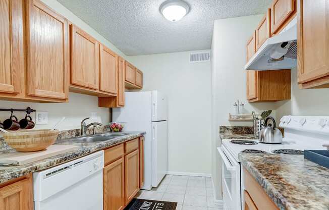 Compact kitchen with warm wood cabinets and white appliances near Montclair area.