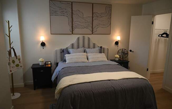 A bedroom with a large bed and a painting on the wall.