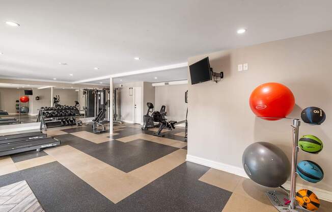 A gym with a variety of equipment including weights and exercise balls.