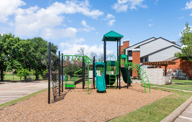 Apartment community playground with climbing structure, slides, and open lawn area.