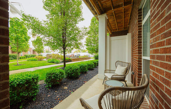 a porch with two chairs and a table on the side of a building