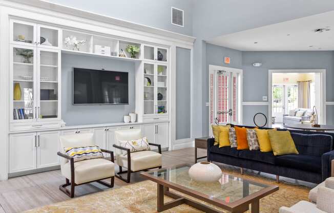 a living room with a black couch and yellow pillows