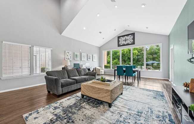 A modern living room with a grey sofa, a wooden coffee table, and a large rug.