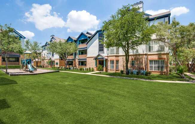 A large grassy area in front of a building with a playground.