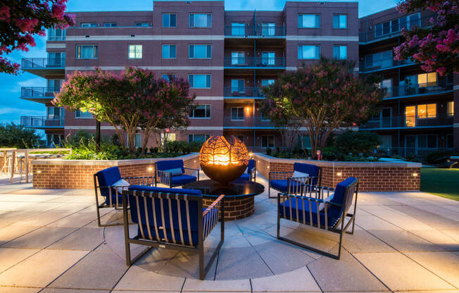 an outdoor patio with chairs and a fire pit at dusk