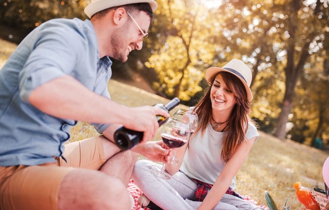 Man and Woman Smiling while Having Picnic and Drinking Wine