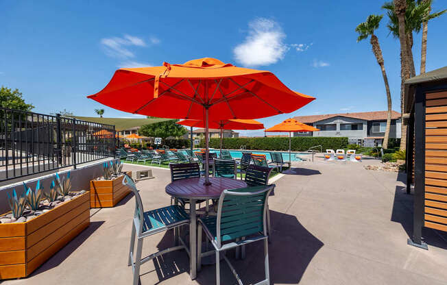 A patio with a table and chairs under an orange umbrella.
