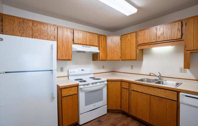 an empty kitchen with white appliances and wooden cabinets. Fargo, ND Westview Towers Apartments