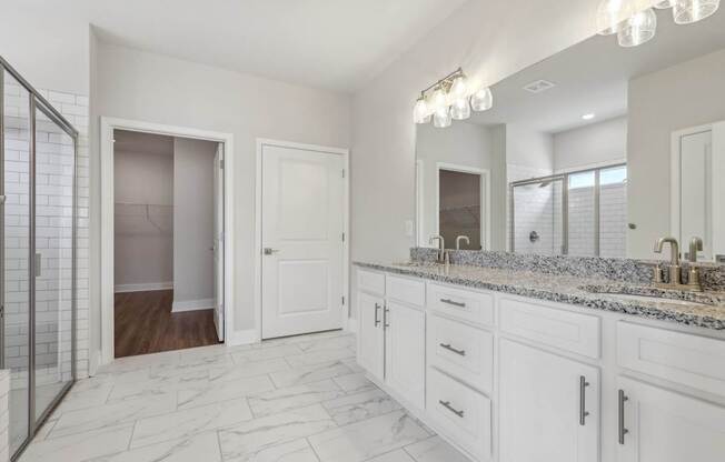 A bathroom with marble flooring and white cabinets.