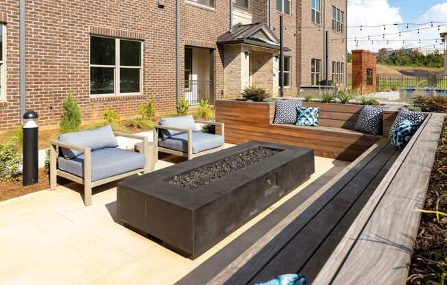 a patio with a firepit and furniture in front of a brick building