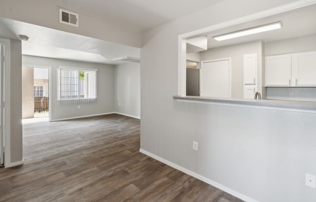 an empty living room and kitchen with white walls and wood flooring