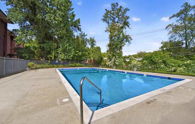A rectangular pool surrounded by a concrete floor and a metal fence.