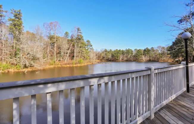 A wooden bridge over a calm body of water with trees in the background.