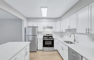 a large white kitchen with white cabinets and stainless steel appliances