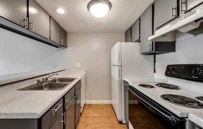 A kitchen with a stove, sink, and refrigerator.
