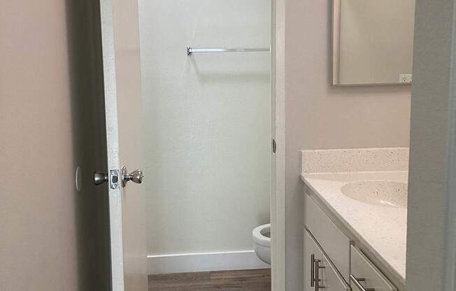 A white bathroom with a toilet, sink, and mirror.