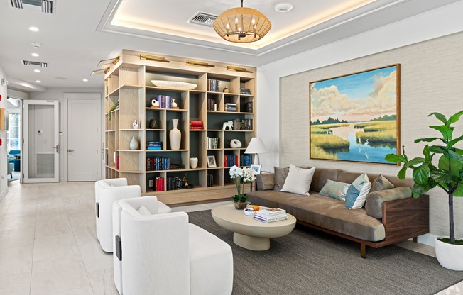 A living room with a bookshelf, a couch, and a painting on the wall.