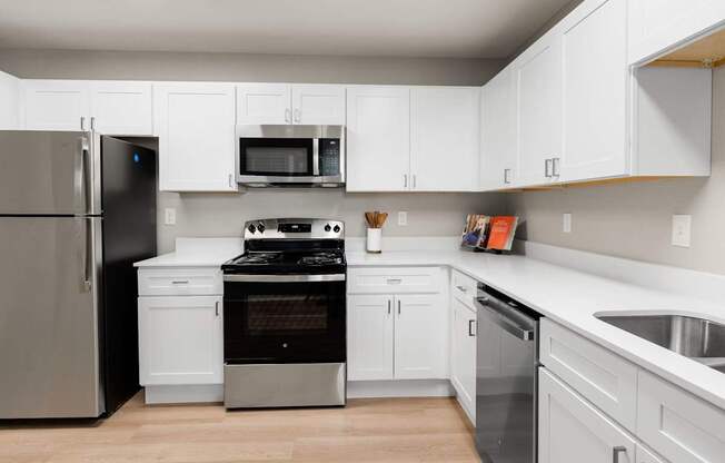 Modern kitchen featuring white shaker cabinets, stainless steel appliances, and expansive countertop workspace.