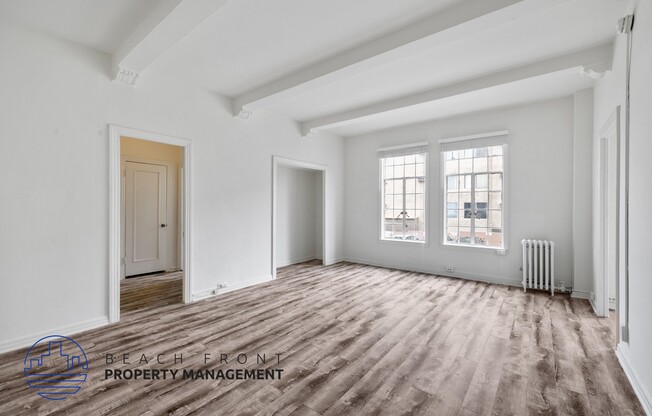 the living room of an apartment with white walls and wood floors