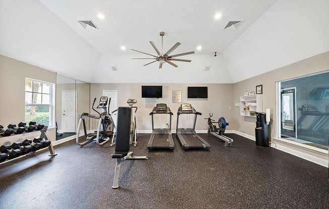 A spacious home gym with a variety of equipment including a treadmill, stationary bike, and weight bench.