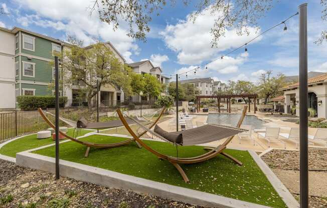 a group of hammocks on a lawn near a pool