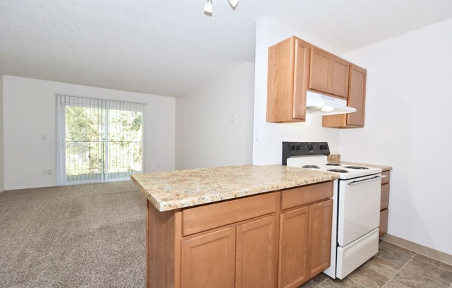 a kitchen with an island and a living room in the background