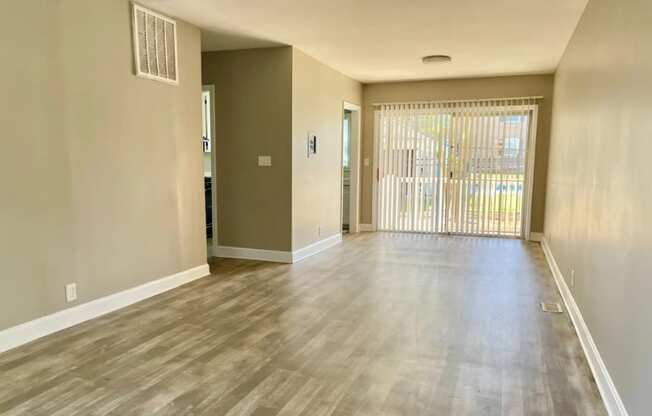 the living room and dining room of an empty home with a sliding glass door