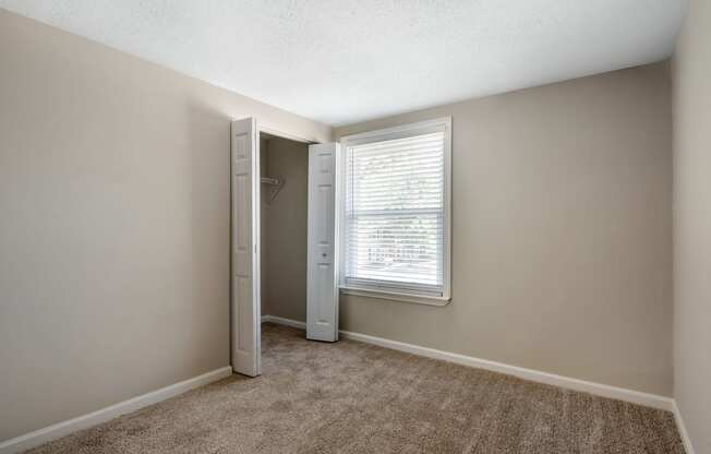 an empty bedroom with a large window and a closet