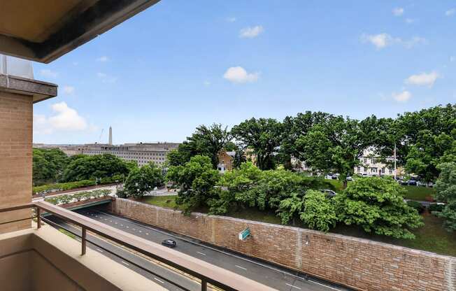 A view from a balcony overlooking a road and greenery.