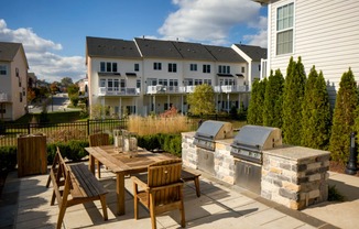 a patio with a table and chairs and a barbecue grill